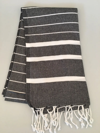 "Gray and white striped Teos Turkish towel with fringed edges, folded neatly on a light surface."