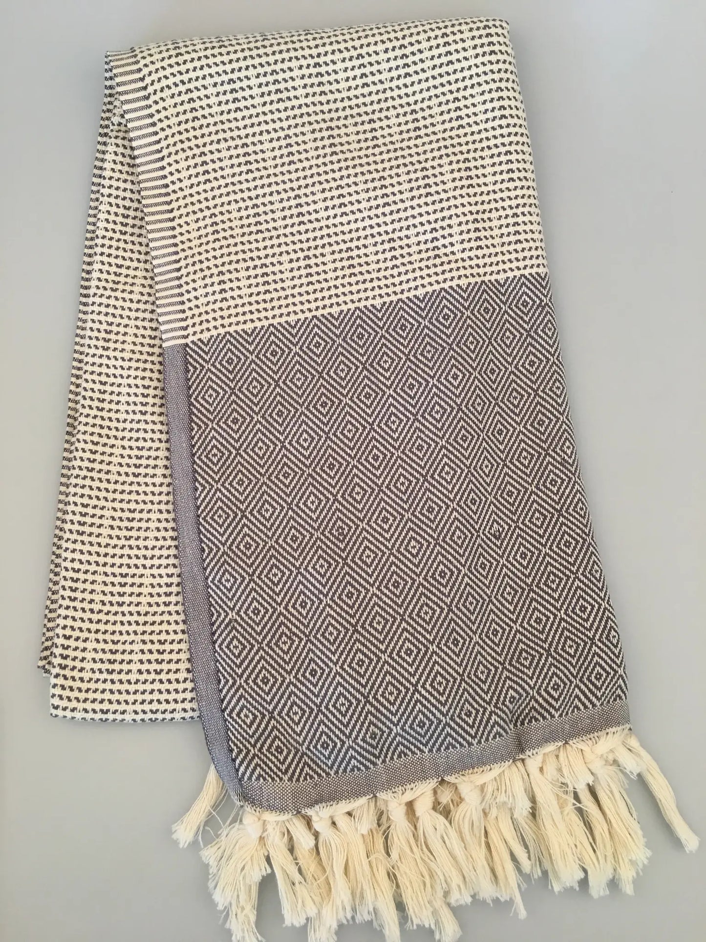 "Lycia Patara Turkish towel peshtemal in beige and gray with diamond pattern and fringed edges, laid flat"
