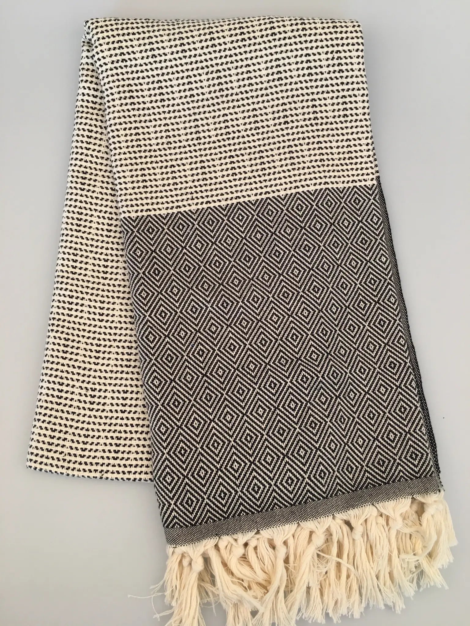 "Lycia Patara Turkish towel peshtemal in cream and gray with geometric patterns and fringed edges, laid flat"