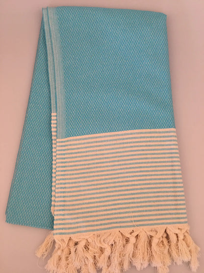 Aqua blue Turkish towel with a textured weave, featuring a striped beige section and fringed edges.