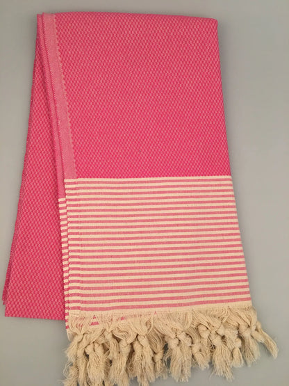 "Pink Miletus Turkish towel with textured pattern, striped cream section, and fringed edges, laid flat"