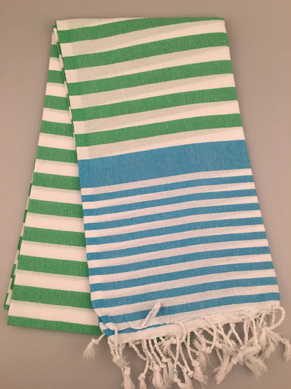 "Striped Turkish towel in green and blue with white stripes, featuring fringed edges, flat lay view"