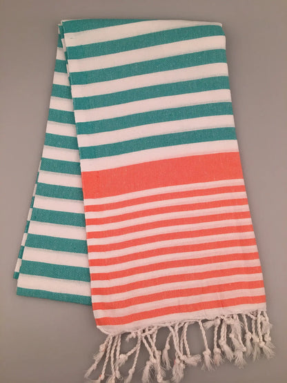 "Striped Turkish towel in turquoise and white with an orange band, featuring fringed ends, folded view."