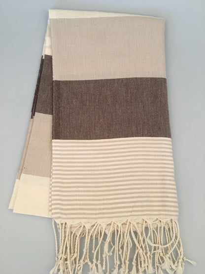 "Beige and brown striped Turkish towel with tassels, featuring a textured weave and smooth stripes."